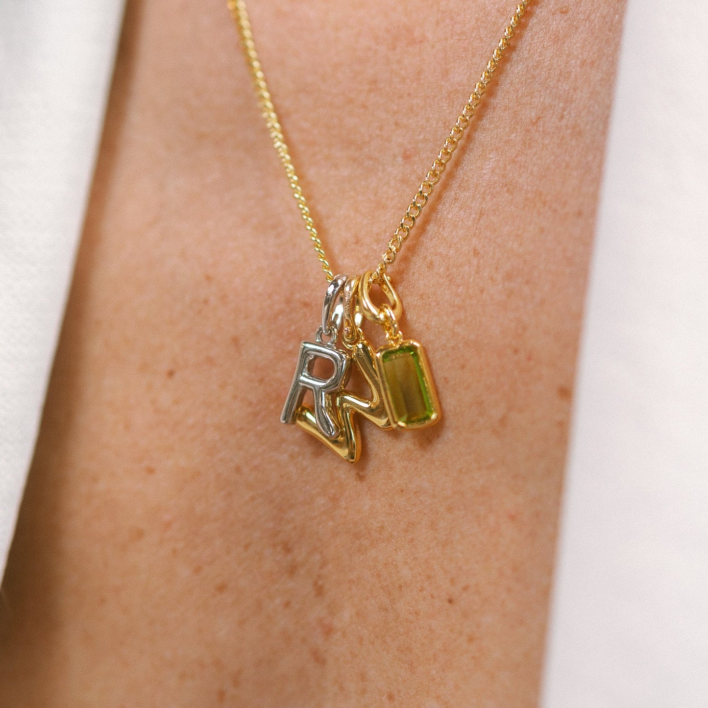 Gold necklace with charms on a person's neck against a white background