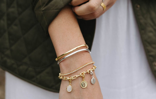 Gold bangle bracelet by Mogano crafted in 14k gold filled or sterling silver with a hinge-style clicker closure. Hypoallergenic, tarnish-resistant jewelry for all skin types.