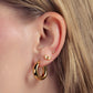 Close-up of an ear wearing gold hoop earrings with a butterfly accent.