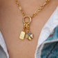 Gold necklace with charms on a person wearing a denim jacket.