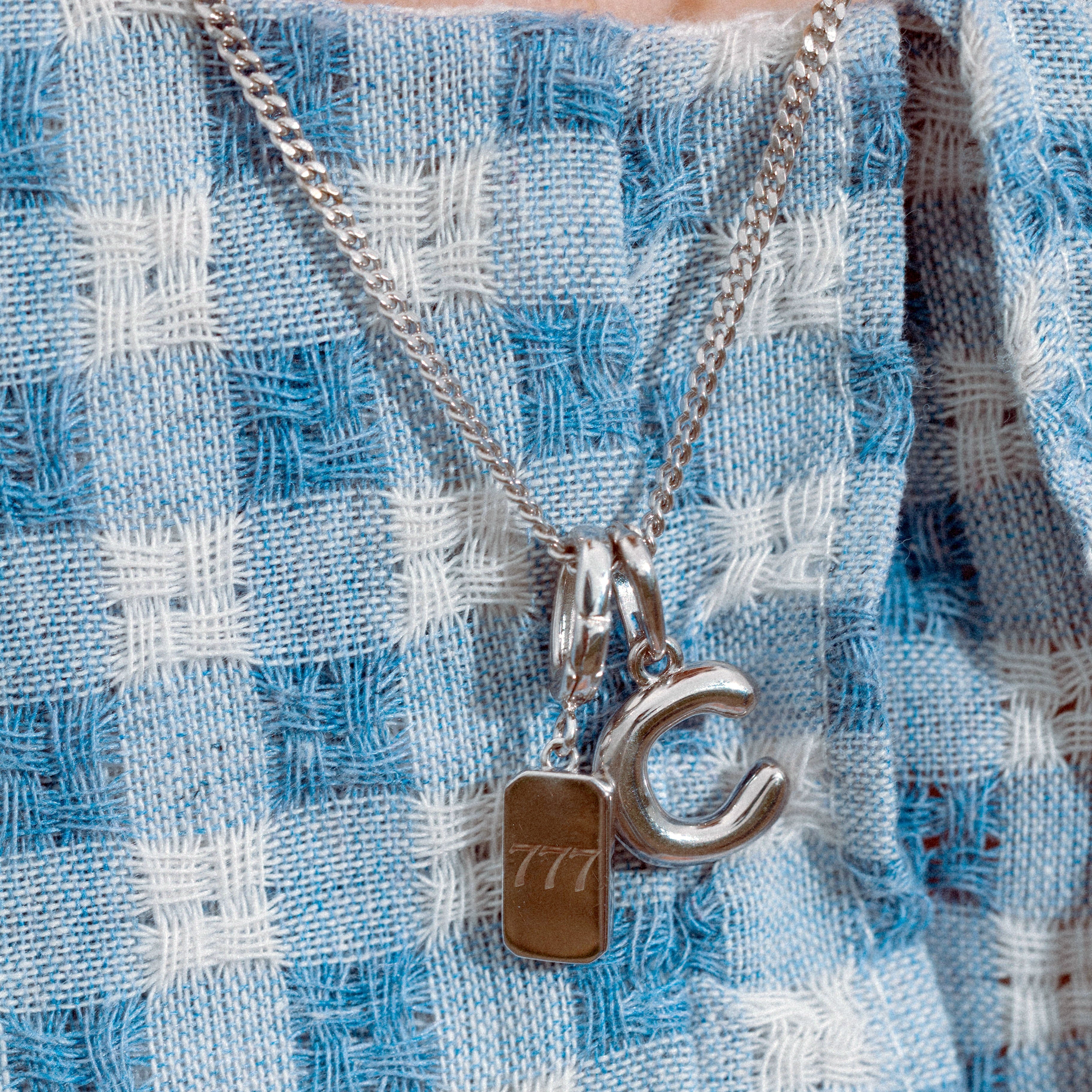 Close-up of a necklace with a pendant on a blue and white checkered fabric background