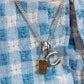 Close-up of a necklace with a pendant on a blue and white checkered fabric background