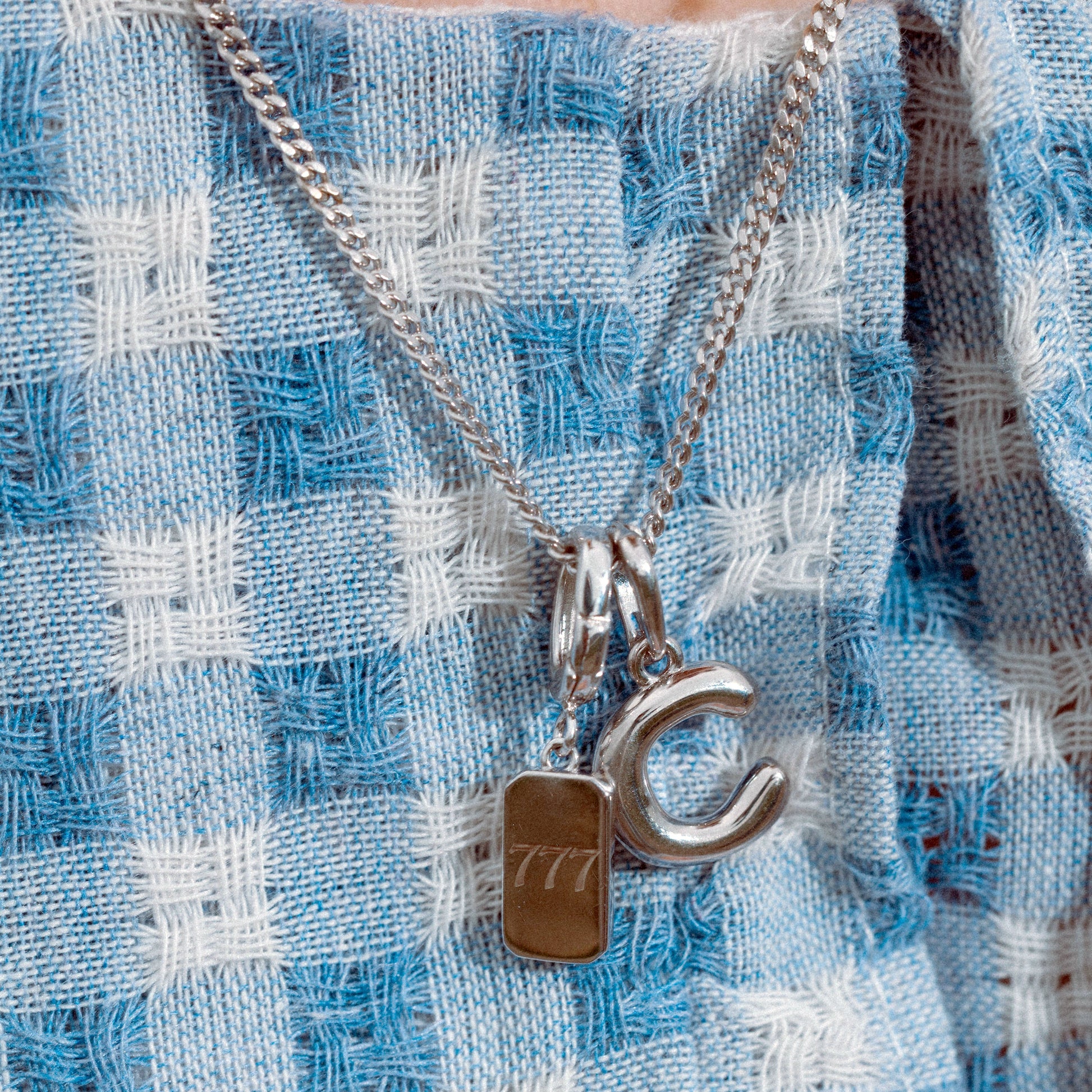 Close-up of a necklace with a pendant on a blue and white checkered fabric background
