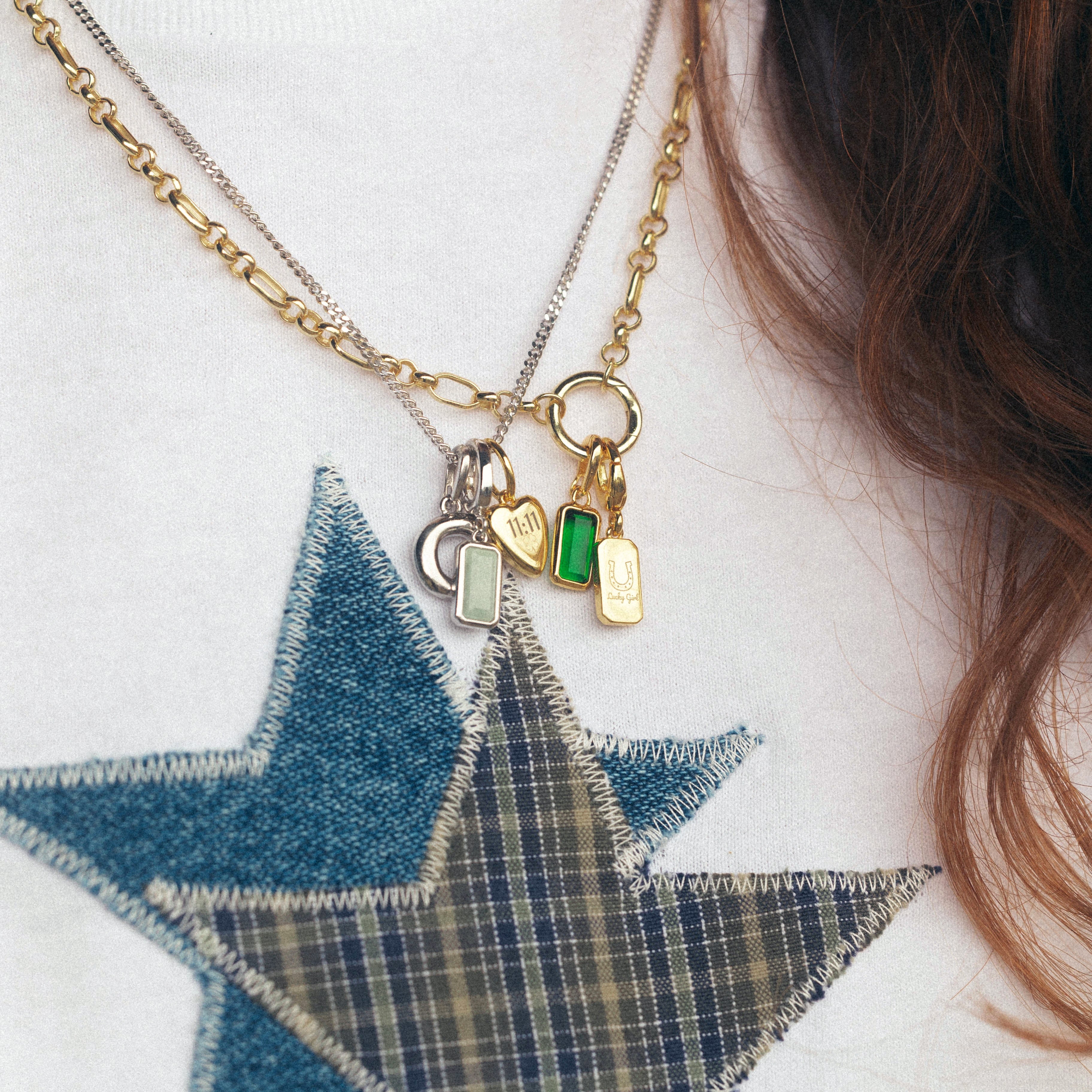 Close-up of a gold necklace with charms on a white sweater with a blue star design.