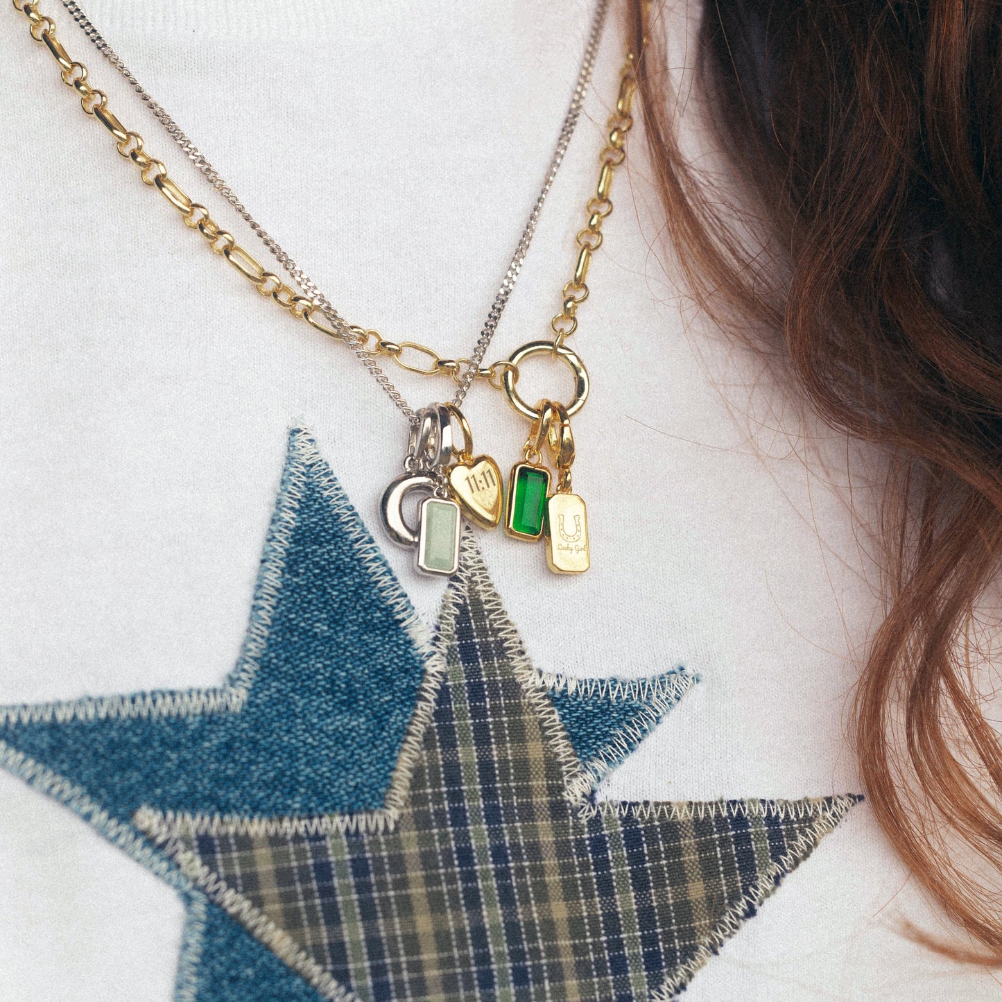 Close-up of a gold necklace with charms on a white sweater with a blue star design.