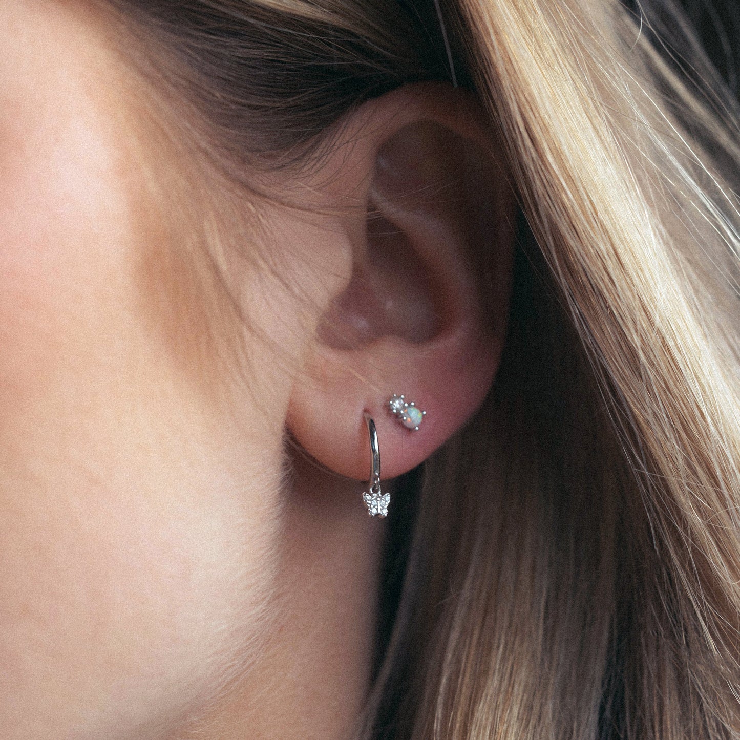 Close-up of an ear wearing a silver earring with a small gemstone.
