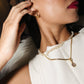 Woman wearing gold earrings and a necklace, with a blurred background