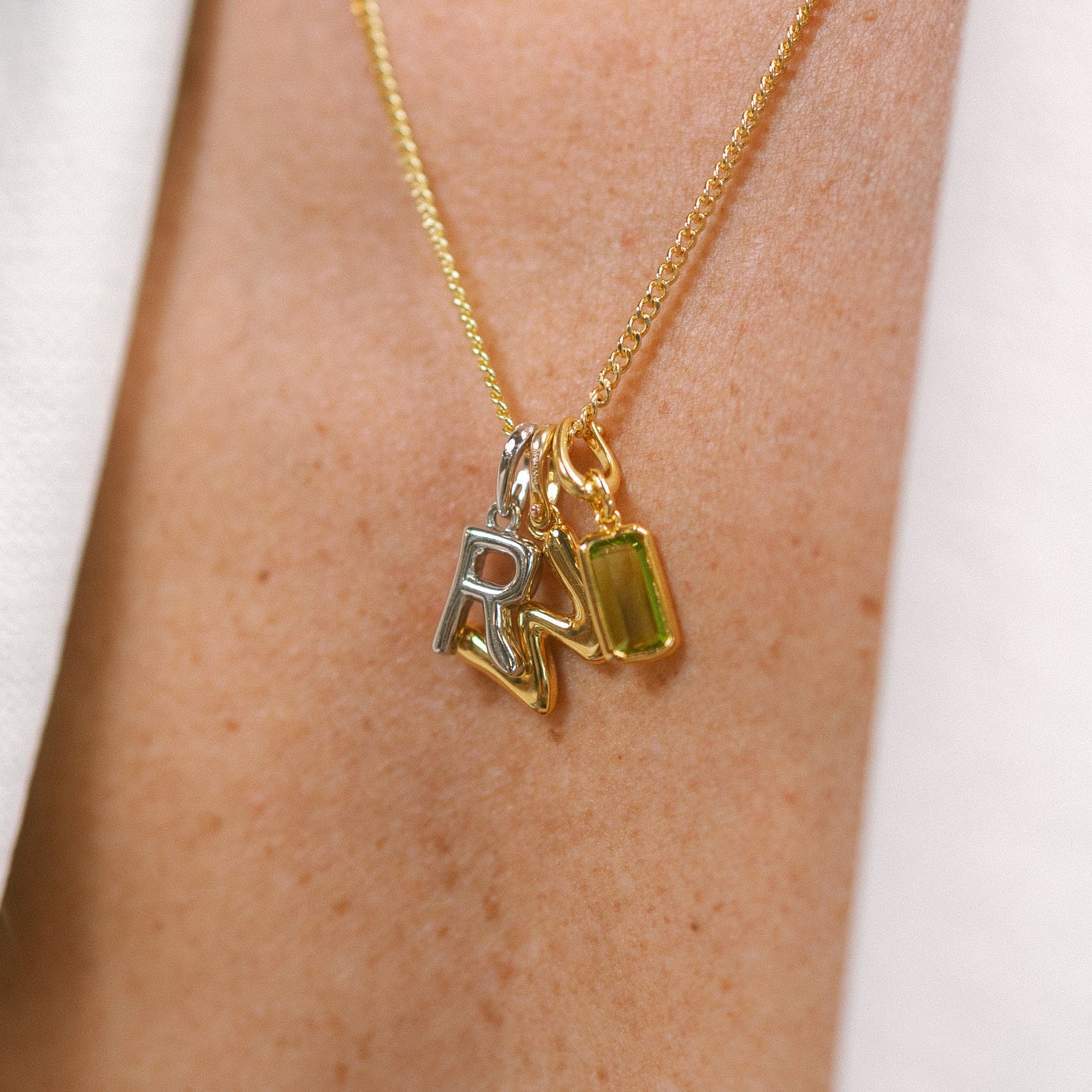 Gold necklace with charms on a person's neck against a white background