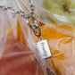 Necklace with a 'fruity' pendant in front of fruits