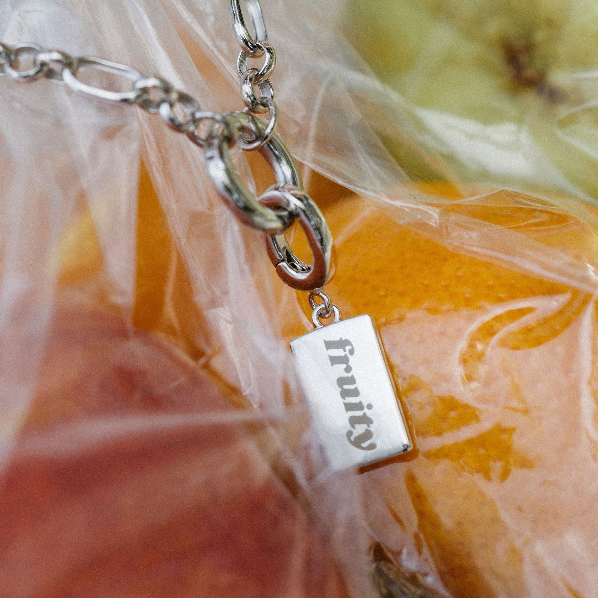 Necklace with a 'fruity' pendant in front of fruits