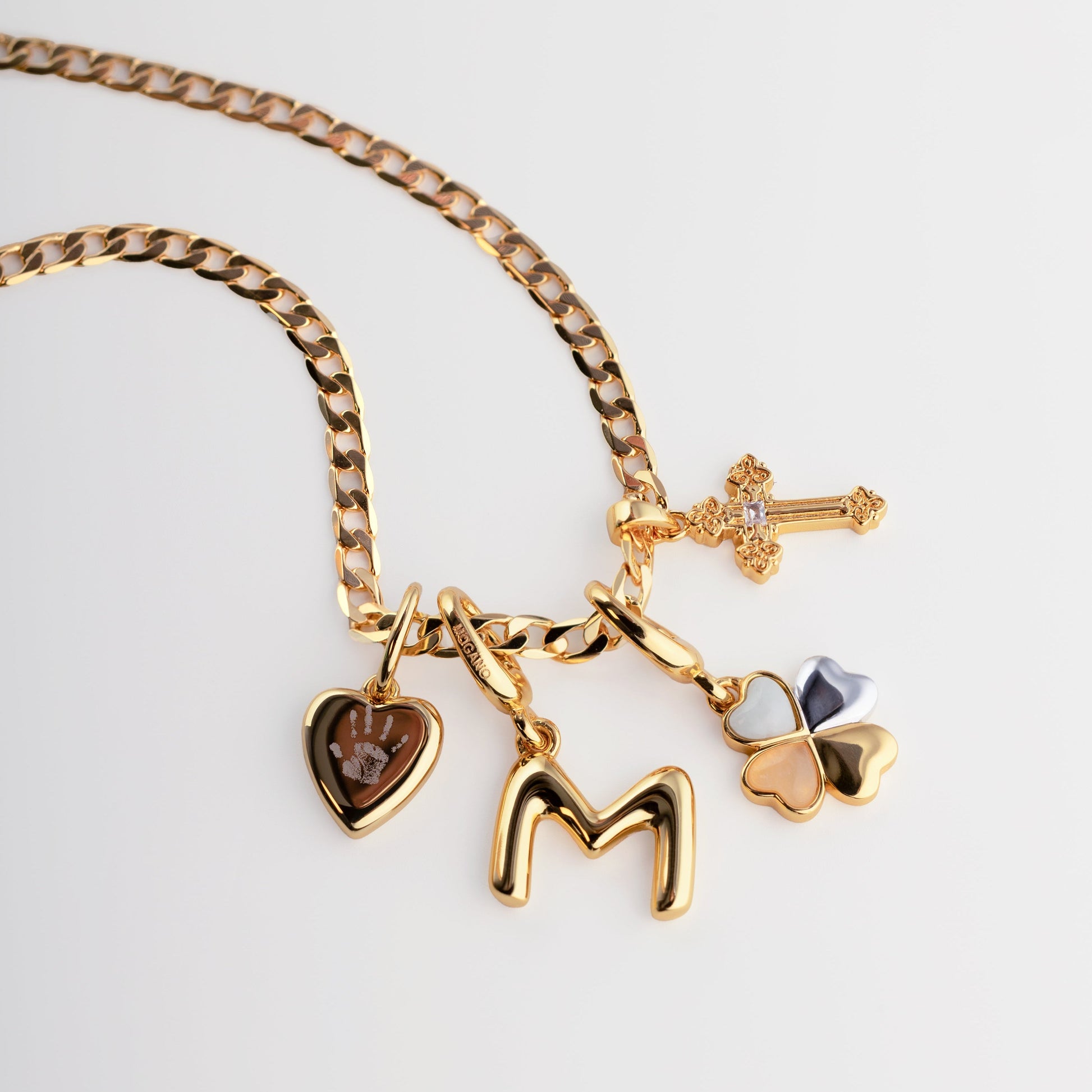 Gold necklace with various charms on a light gray background