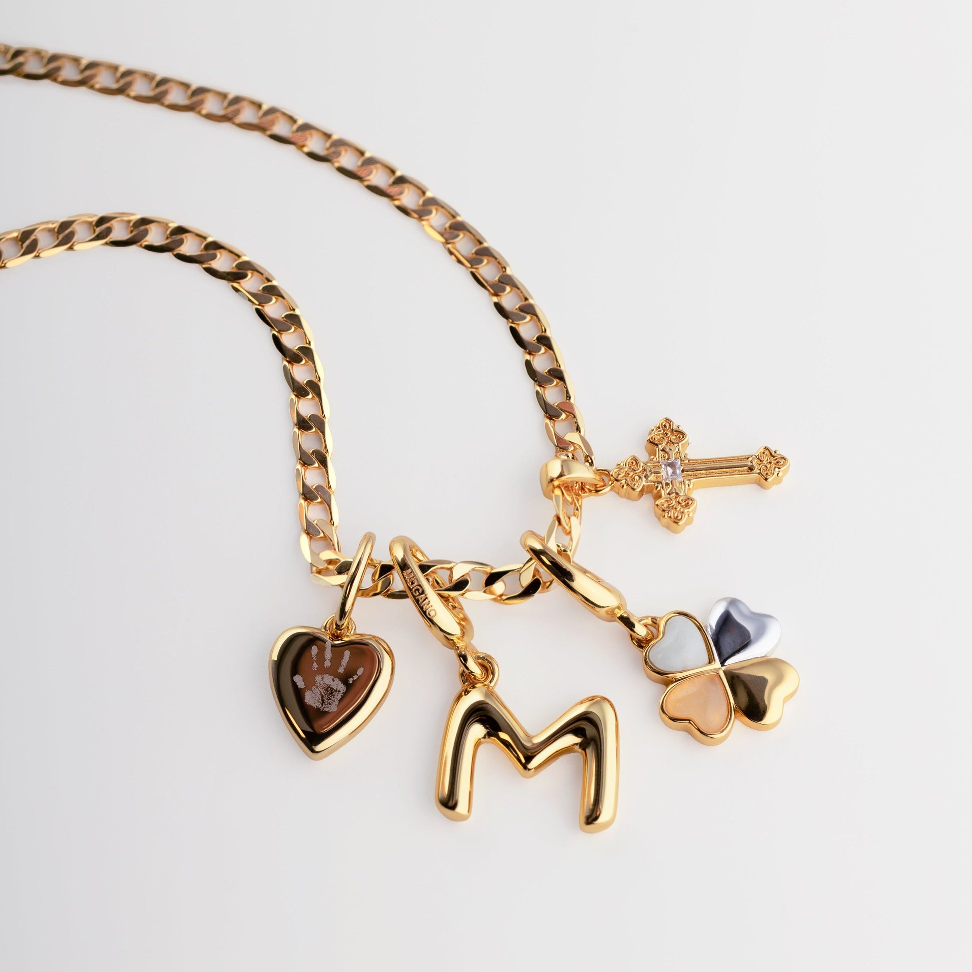 Gold necklace with various charms on a light gray background