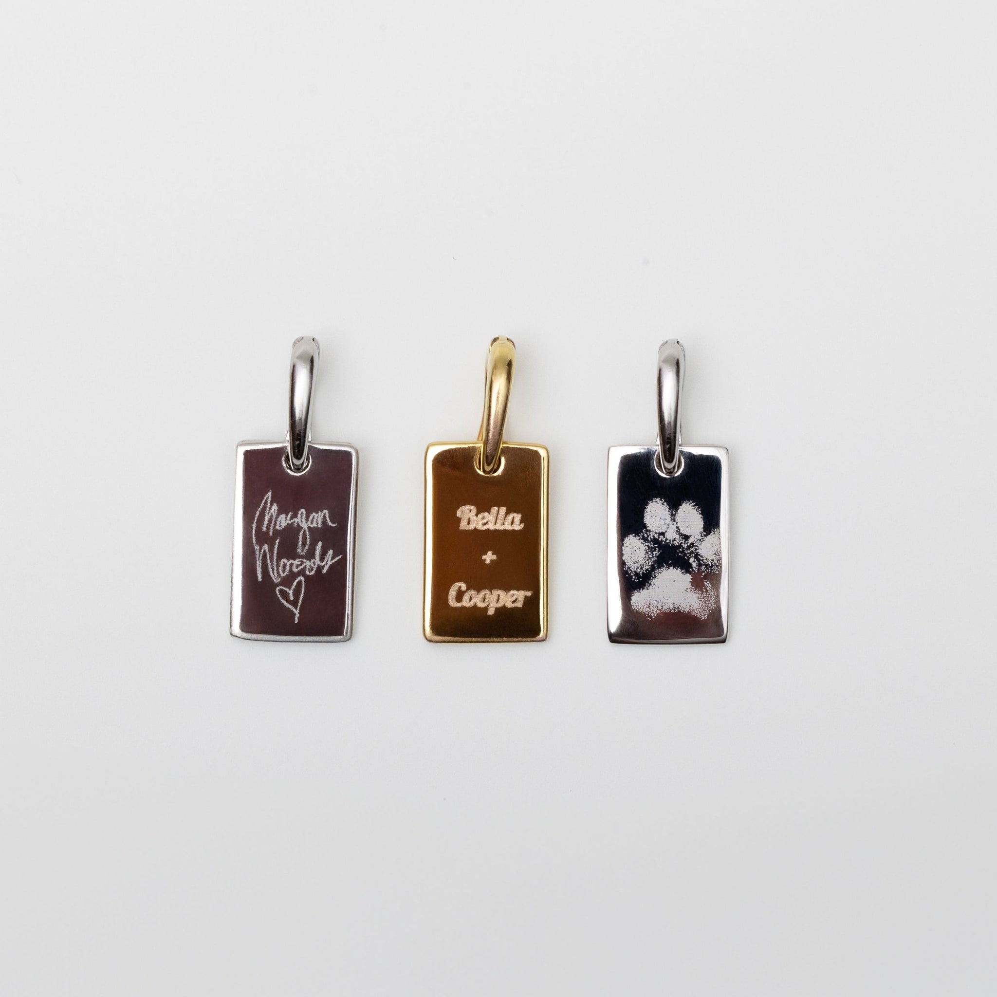 Three rectangular dog tag flat rectangle charms with different engraving designs on a white background