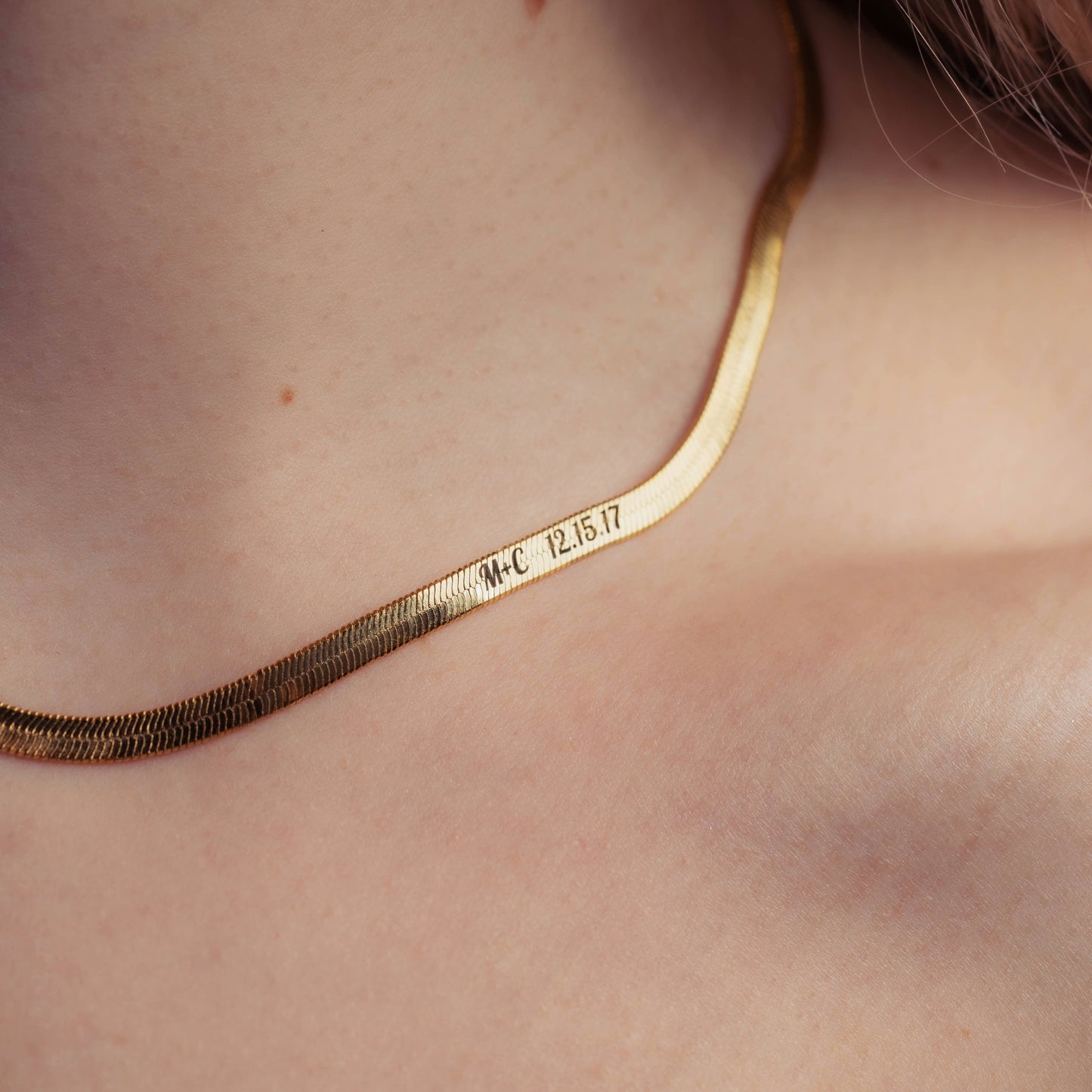 Gold necklace with engraved text on a person's neck