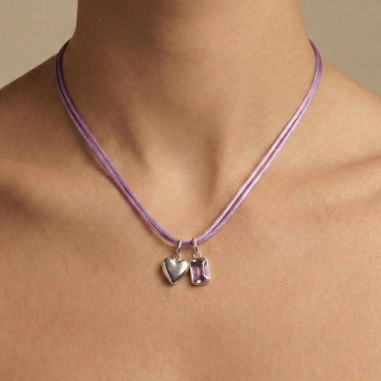 Purple Cord Necklace with heart and rectangular pendant on a person against a neutral background