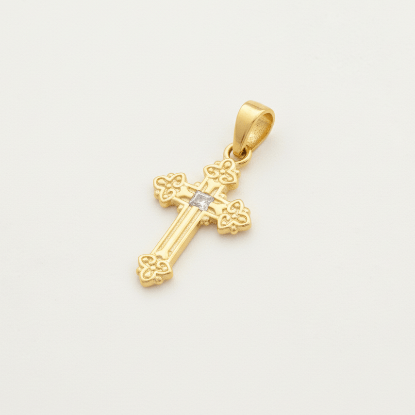 Gold cross pendant with a diamond on a light gray background