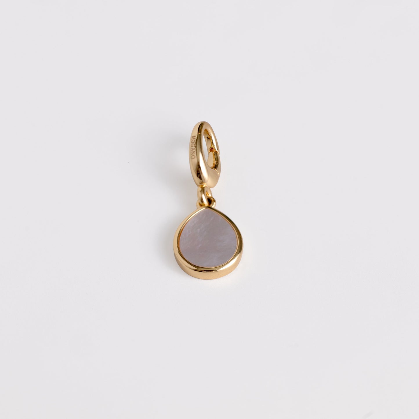 Gold pendant with a teardrop-shaped gemstone on a light gray background
