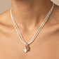 Necklace with pendant on a person's neck against a neutral background