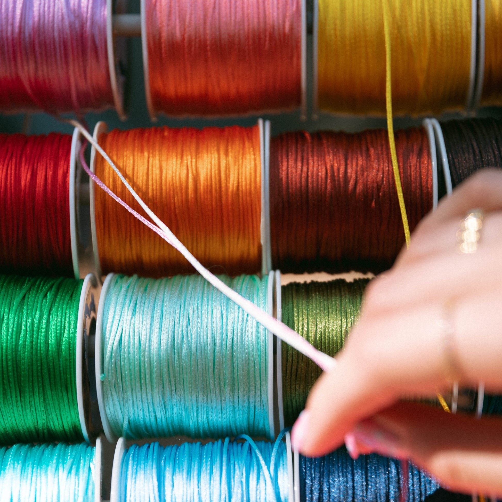 Colorful spools of thread with a hand selecting a thread color.