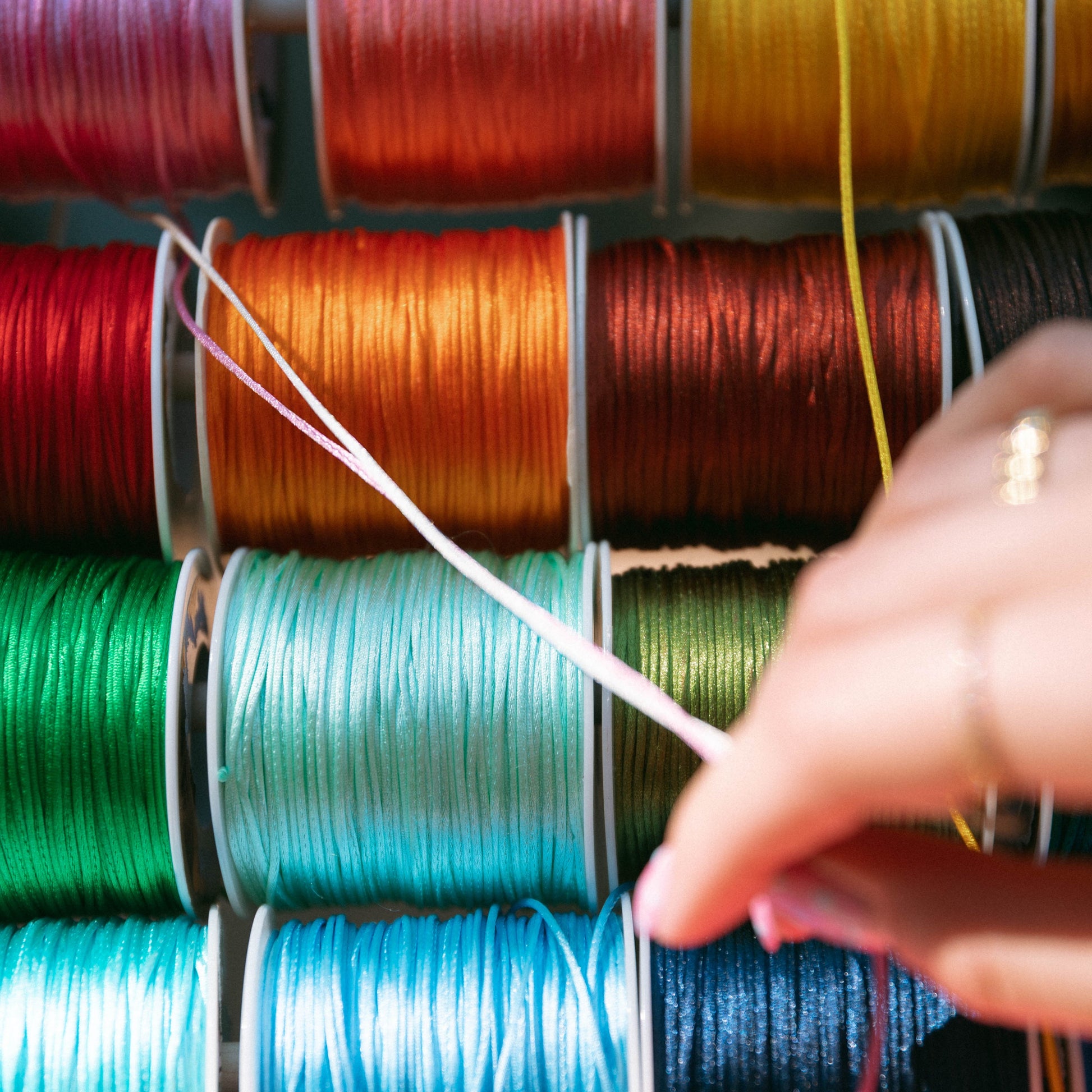 Colorful spools of thread with a hand selecting a thread color.