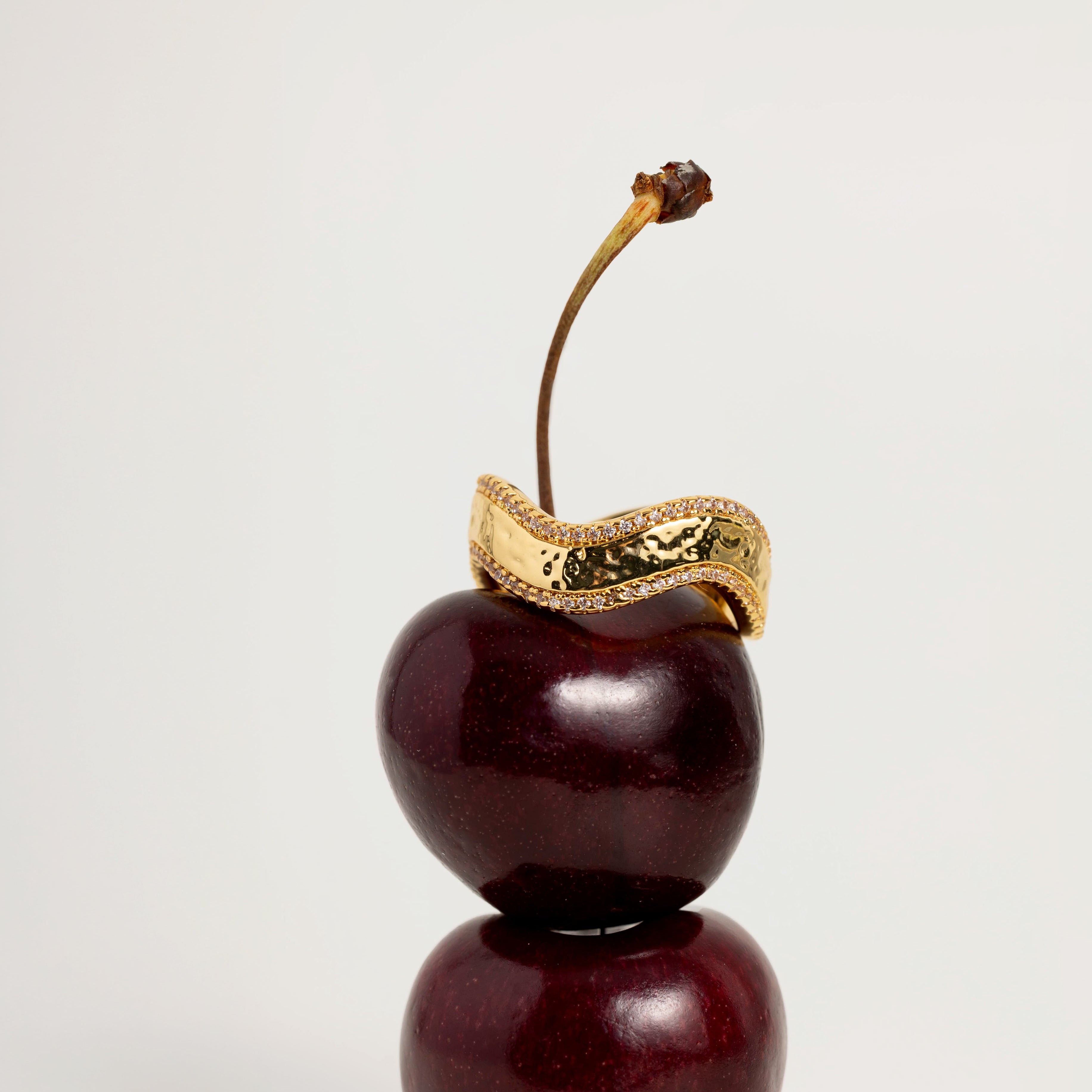 Decorative cherry with a gold ring on a white background