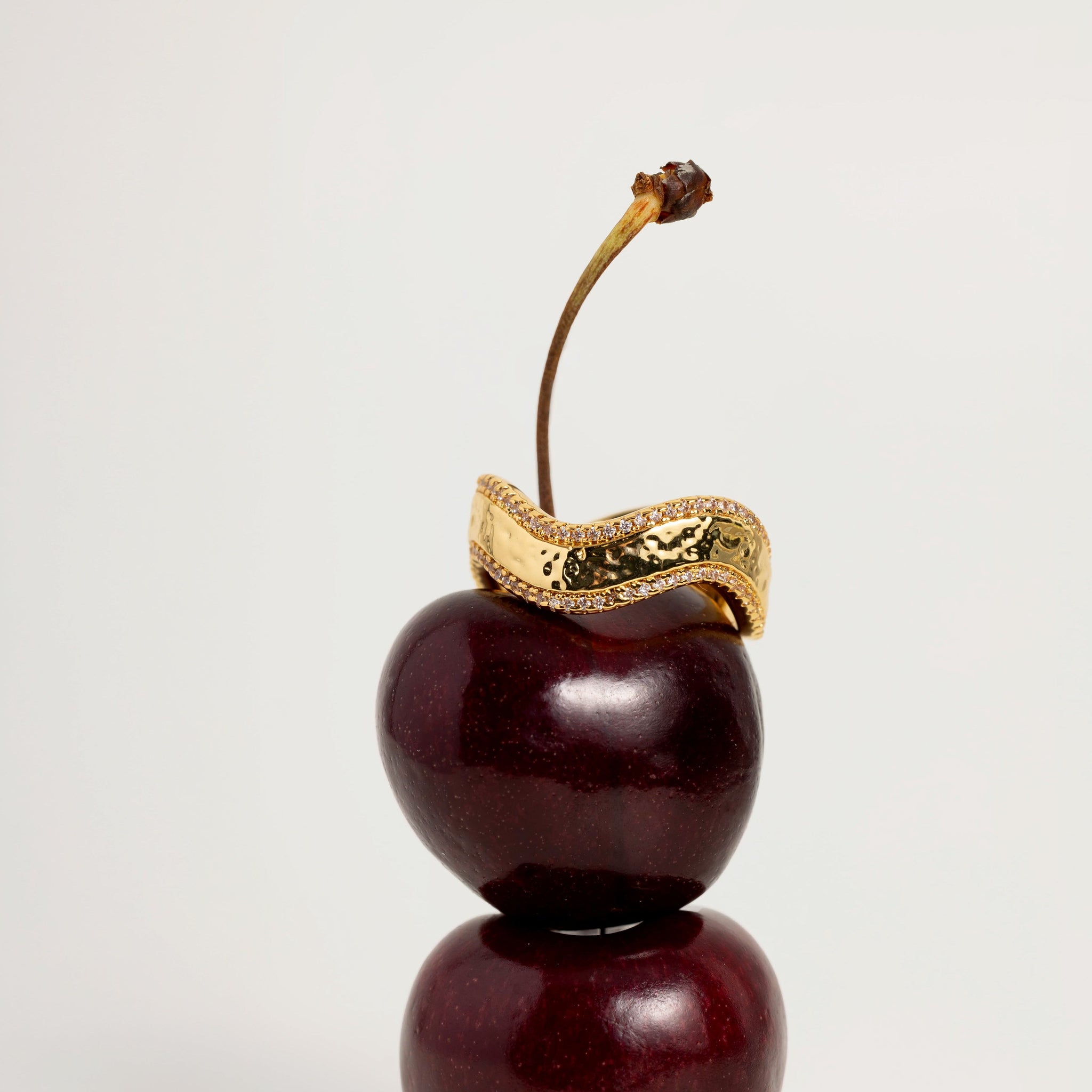 Decorative cherry with a gold ring on a white background