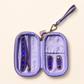 A lavender purple jewelry organizer pouch shown open, featuring a wrist strap, zipper compartment, and two iridescent purple-and-blue barrette holders on a light beige background.
